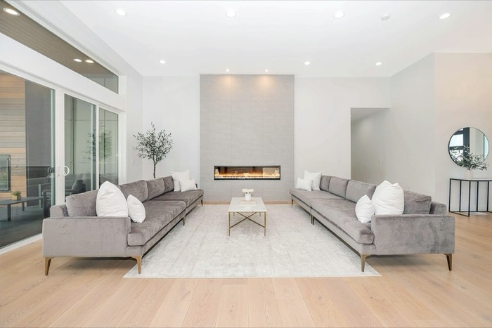 A bright modern living room with two grey velvet sofas facing each other across a marble coffee table.